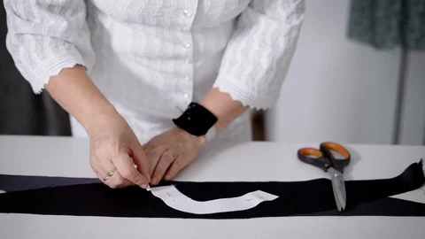 Dressmaker holding template and drawing clothes piece on fabric Stock Footage