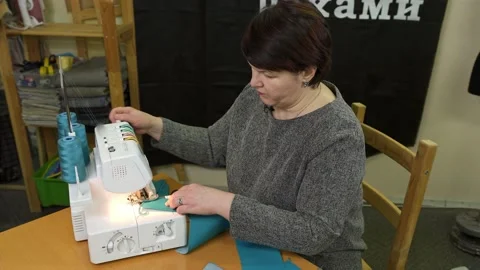 Dressmaker working on a sewing machine in her studio at table. Stock Footage 136098081