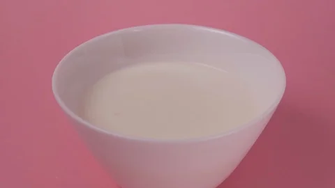 Dried apricots fall into a white plate with yogurt. Vidéo 126588877