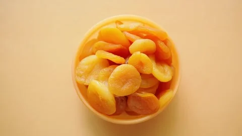 Dried apricots in a yellow container on a plain background Stock Footage 336423421