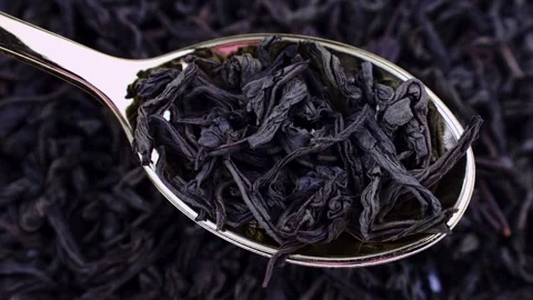 Dried black ted leaves in the spoon with circle rotation close up Stock Footage 244302249