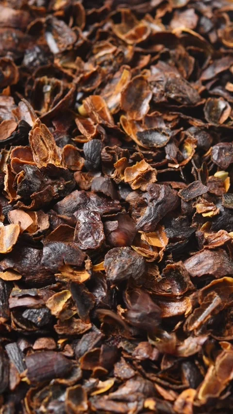 Dried cascara coffee cherry husks rotate as more pieces fall from above in macro Stock Footage 346200872