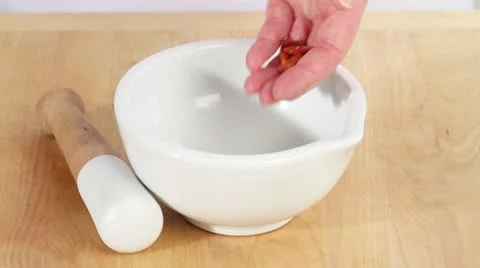 Dried chilli peppers being added to a mortar and ground 스톡 동영상 24655593