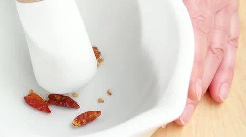 Dried chilli peppers being ground in a mortar Stock Footage 24655595