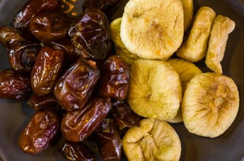 Dried dates and figs in a ceramic plate on a wooden table Stock Photos