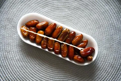 Dried dates are placed in a white dish a pitting tool Stock Photos
