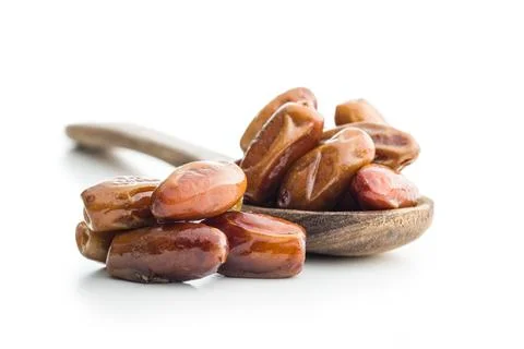 Dried dates fruit in spoon isolated on white background. Stock Photos