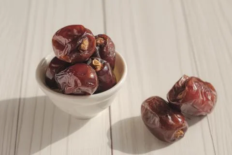 Dried dates in a white ceramic bowl in the bright sun Stock Photos