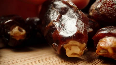 Dried dates on a wooden table, I examine them in my hand as the camera moves for Stock Footage 237368935