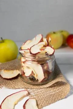 Dried dehydrated apple chips in glass jar on white background Stock Photos
