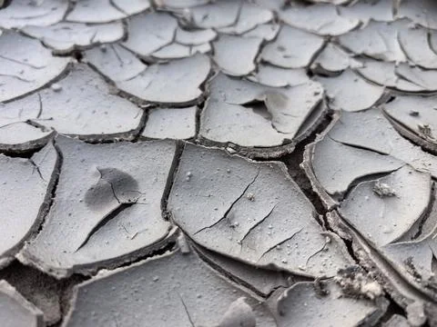 Dried earth reveals cracking patterns under scorching sunlight Stock Photos