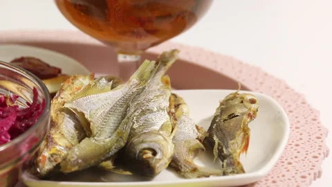 Dried fish, beer and salad on a tray. The man eats fish and drinks beer. Clos Stock Footage 145484753