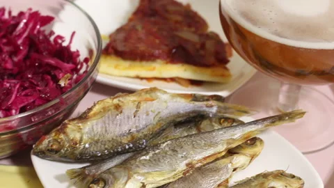 Dried fish, beer and salad on a tray. The man eats fish and drinks beer. Near Stock Footage 145484884