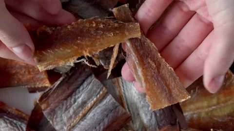 Dried fish fillet red cod amber. An appetizer for beer. Woman tearing up the Stock Footage 229791548