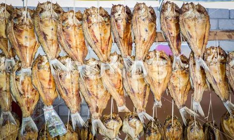 Dried fish hang on wooden drying rack Stock Photos