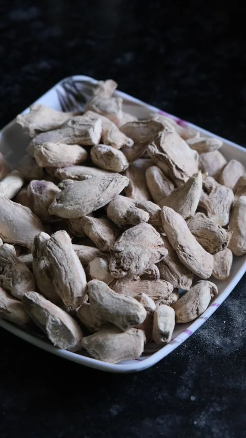 Dried ginger roots piled in a white square plate on a dark surface Vidéo 331987387