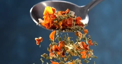Dried herbs and spices falling from a spoon in slow motion on blue background Stock Footage 346255790