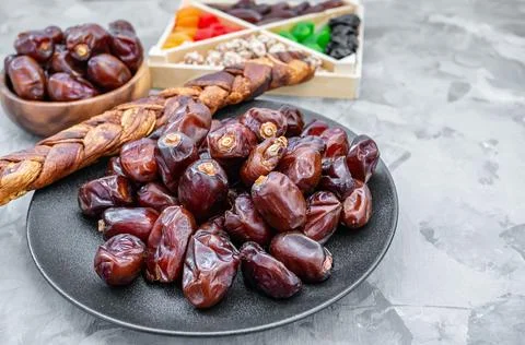 Dried large dates and a spit of dried melon lie on a black plate. Close-up Stock Photos