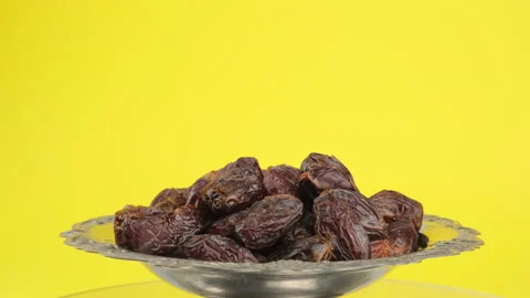 Dried large dates on a metal plate that rotates, yellow background, majul variet Stock Footage 147705520