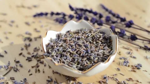 Dried lavender flowers falling from above in porcelain bowl on wooden table Stock Footage 151226571