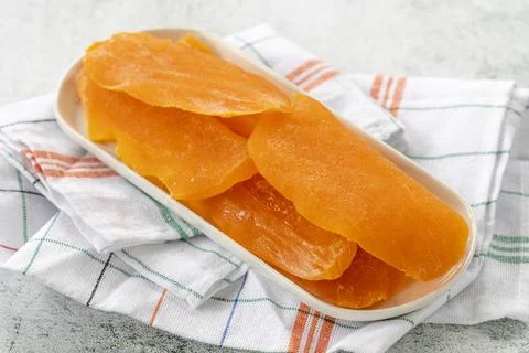 Dried mango slice on gray background. Dried fruit in sunlight. close up Stock Photos