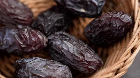 Dried medjool dates falling into a wooden rattan bowl Video stock 273295257