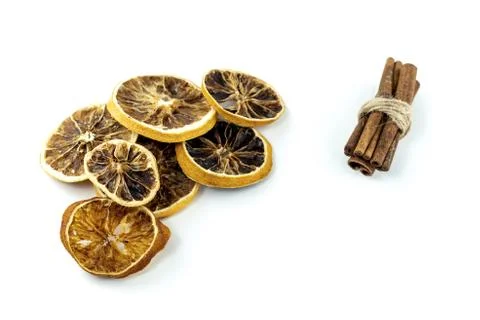 Dried orange a round piece in a stack and a bunch of cinnamon on a white back Stock Photos