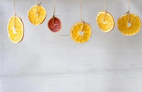 Dried orange slices hang on strings on a white wooden background Stock Photos