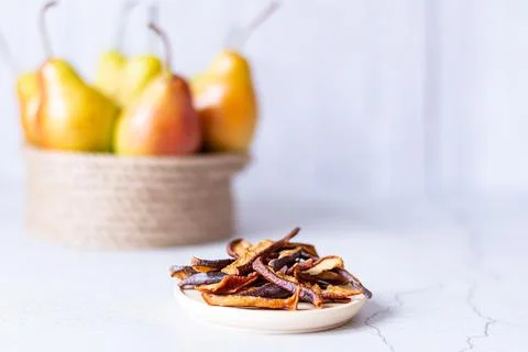 Dried pears on a light background next to a basket of fresh pears 스톡 사진