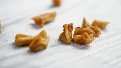 Dried pineapple pieces falling on a white wooden surface Stock Footage 271230605
