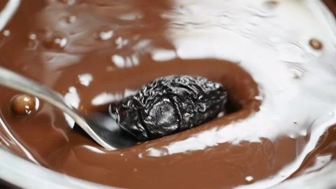 Dried plum is dipping into melted dark chocolate. Stock Footage 171936832