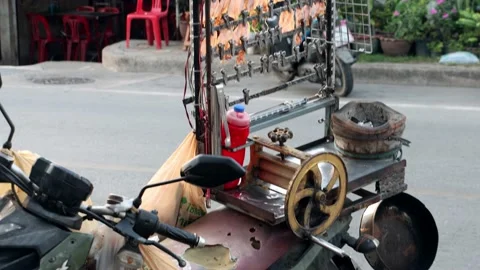 Dried pressed squid hang from a holder mounted on a street vendor's motorbike Stock Footage 237139031