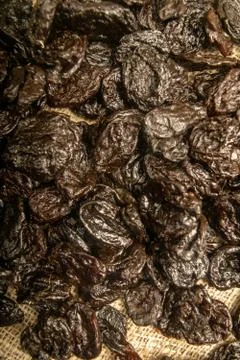 Dried prunes in bulk on burlap with a rough texture. Close up. Stock Photos