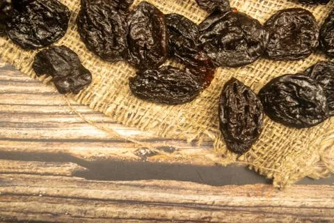 Dried prunes in bulk on burlap with a rough texture. Close up. Stock Photos