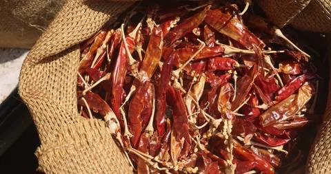 Dried red pepper is sold at the local market on a sunny day in a burlap bag. Video stock 235883130