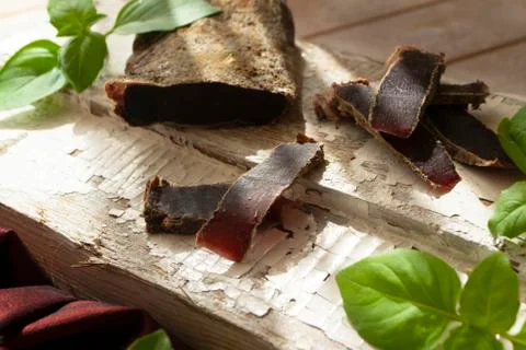 Dried roe deer meat on a rustic shabby cutting board Stock Photos