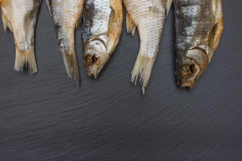 Dried salted roach on black background of slate or stone. Stock Photos