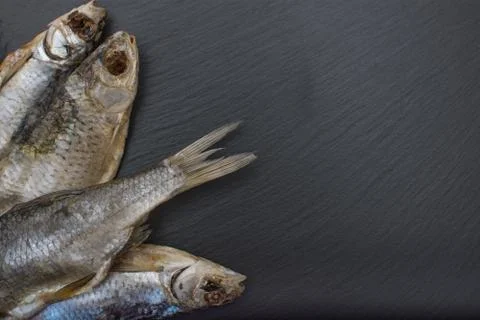 Dried salted roach on black background of slate or stone. Stock Photos
