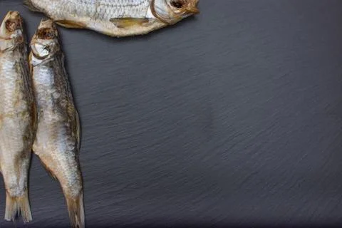 Dried salted roach on black background of slate or stone. Stock Photos