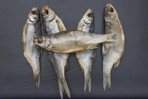Dried salted roach on black background of slate or stone. Stock Photos