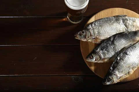 Dried salted roach fish and beer on wooden table, flat lay. Space for text Stock Photos
