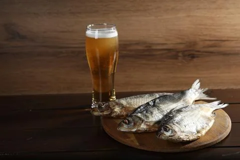 Dried salted roach fish and beer on wooden table, closeup. Space for text Stock Photos