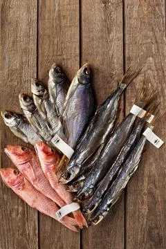 Dried salted roach, sabrefish and red mullets with labels on tails on wooden Foto stock