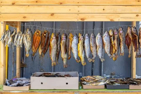 Dried smoked fish displayed in rustic outdoor market stall Фото