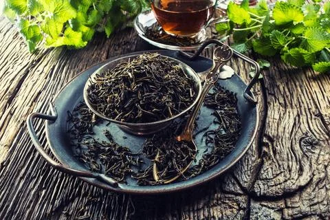Dried tea leaves in bowl on rustic wooden table Stock Photos