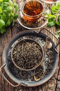 Dried tea leaves in bowl on rustic wooden table Stock Photos