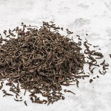 Dried tea is piled on a marble table. Stock Photos