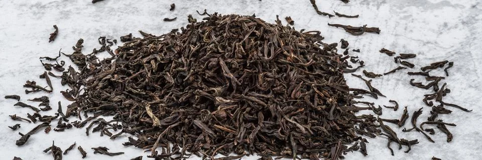 Dried tea is piled on a marble table. Stock Photos