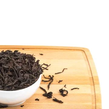 Dried tea is poured into a ceramic cup on a wooden board on a white backgroun Stock Photos