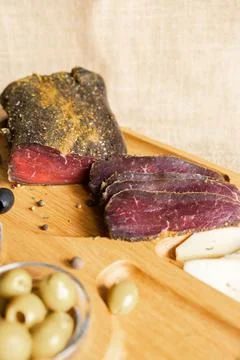Dried tenderloin of beef meat, thinly sliced, on the wooden serving board wit Stock Photos